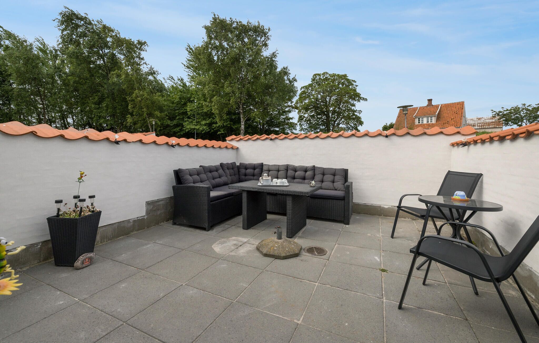 Une terrasse avec un canapé d’angle, une petite table et deux chaises.