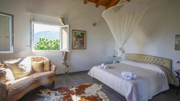 Ein Schlafzimmer mit Bett, Stuhl, Kuhfellteppich, Fenster mit Aussicht und Baldachin.