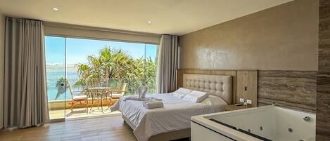 A modern hotel room with a large bed, a separate sitting area with a view, and a standalone bathtub.