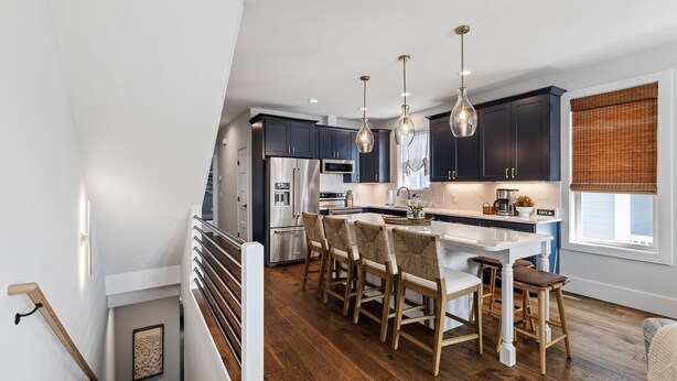 A modern kitchen with dark cabinets, stainless steel appliances, and a central island with bar stools.