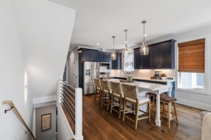 Une cuisine moderne avec des meubles de couleur sombre, des appareils en acier inoxydable et un îlot central doté de tabourets de bar.