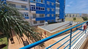 Un balcón con barandilla azul que da a un edificio de paredes exteriores azules y blancas.