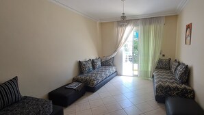 Una habitación con dos sofás, televisión y una puerta corrediza de vidrio a un balcón.