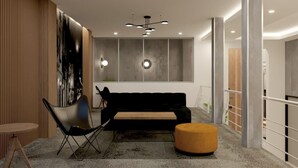 Et moderne interiør med en sort sofa, en træstol, en rund skammel og en tidssvarende lampe.