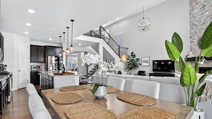 Een moderne keuken met donkere kastjes, een centraal eiland en een eethoek met een houten tafel en geweven placemats.