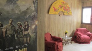 A room with a wooden wall, a movie poster, a yellow fan, and two red chairs. - Hotel Mar de Ajo (Mar de Ajo)