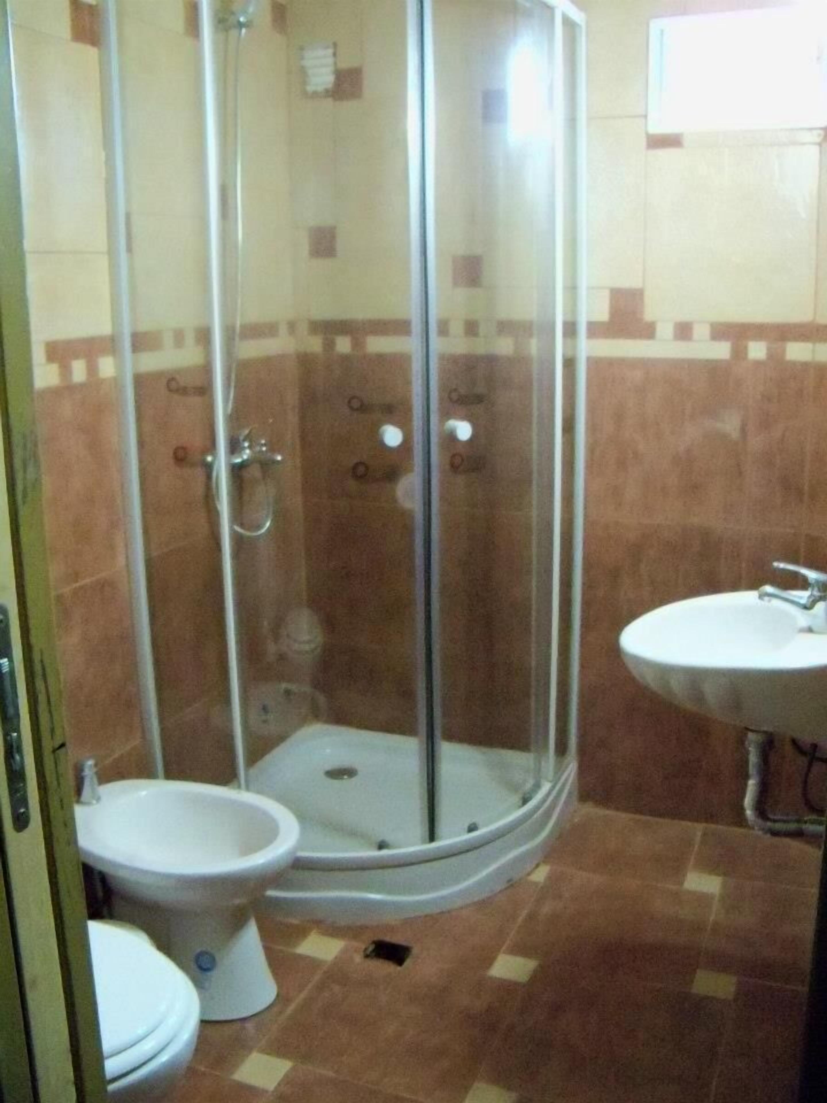 Un baño con ducha de vidrio, inodoro y lavamanos.