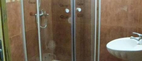 Un baño con ducha de vidrio, inodoro y lavamanos.