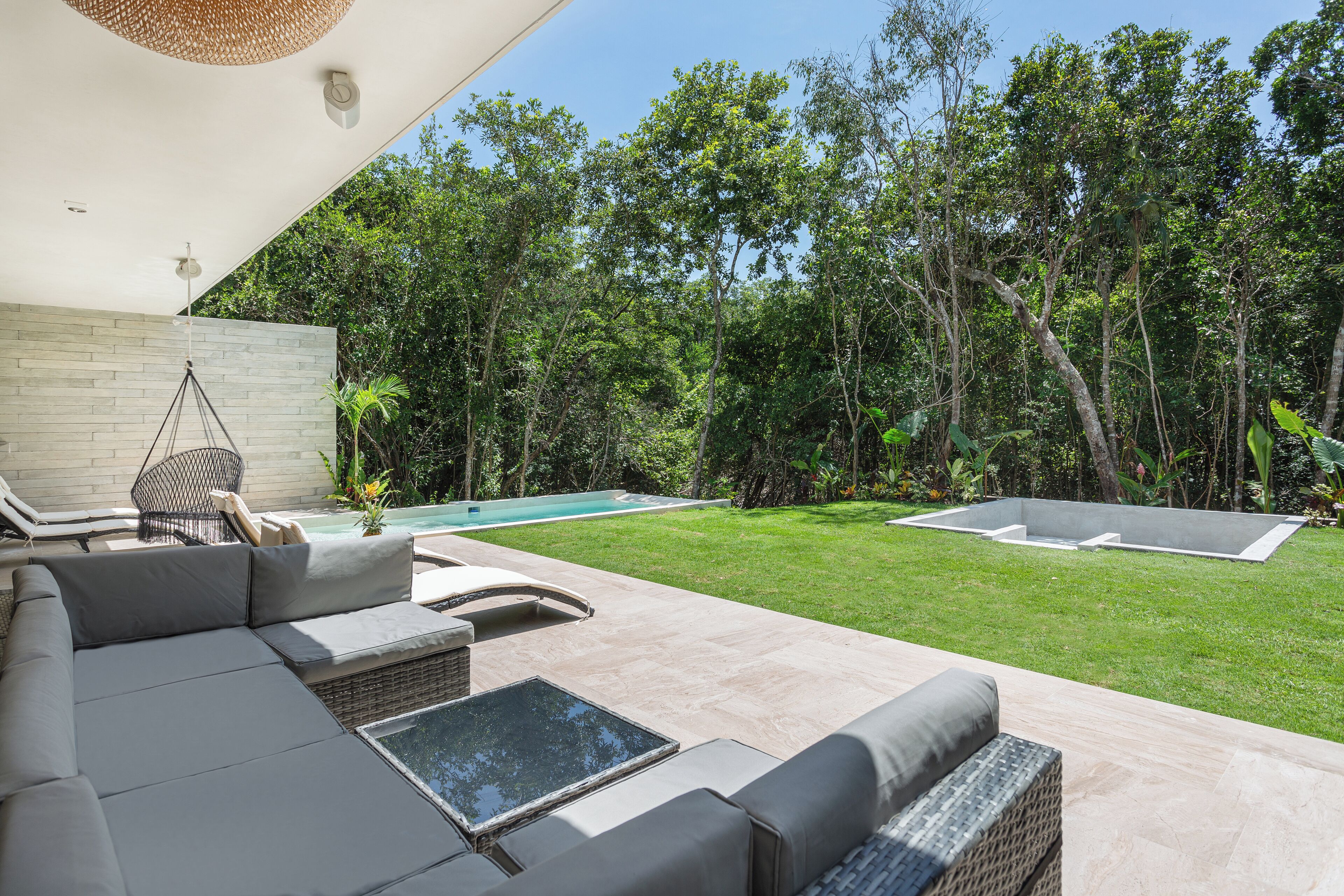 Un espacio exterior moderno con piscina, sillas de descanso y césped cuidado.