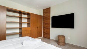 Une chambre à coucher avec un lit, une armoire, un téléviseur et un panier en osier.