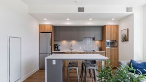 A modern kitchen with a central island, stainless steel appliances, and wooden cabinetry. - Lakeside Retreat w/ Rooftop Pool, Hot Tub, Firepits & BBQs – 10 min to Downtown (Kelowna)