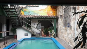 A courtyard with a swimming pool, a staircase, and a mural on the wall. - Hotel San Juan de León (León)