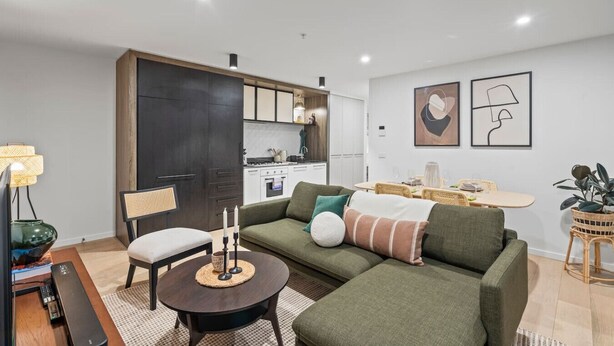 En moderne stue med en hjørnesofa, et rundt sofabord og et spiseområde med bord og stole.