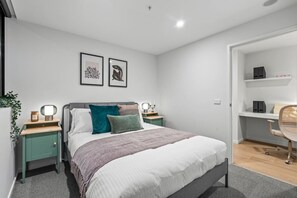 A modern bedroom with a bed, bedside tables, a desk, and a chair.