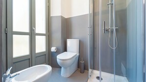 Un bagno moderno con toilette, bidet e cabina doccia in vetro.