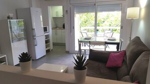 Une cuisine moderne avec des meubles blancs, un réfrigérateur et un coin repas comprenant une table et des chaises.