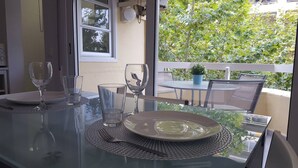Une table à manger dressée avec des assiettes, des verres et des couverts, donnant sur un paysage verdoyant.