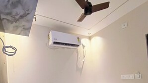 A bedroom with a bed, a ceiling fan, and an air conditioning unit. - Shree murlidhar Residency (Varanasi)