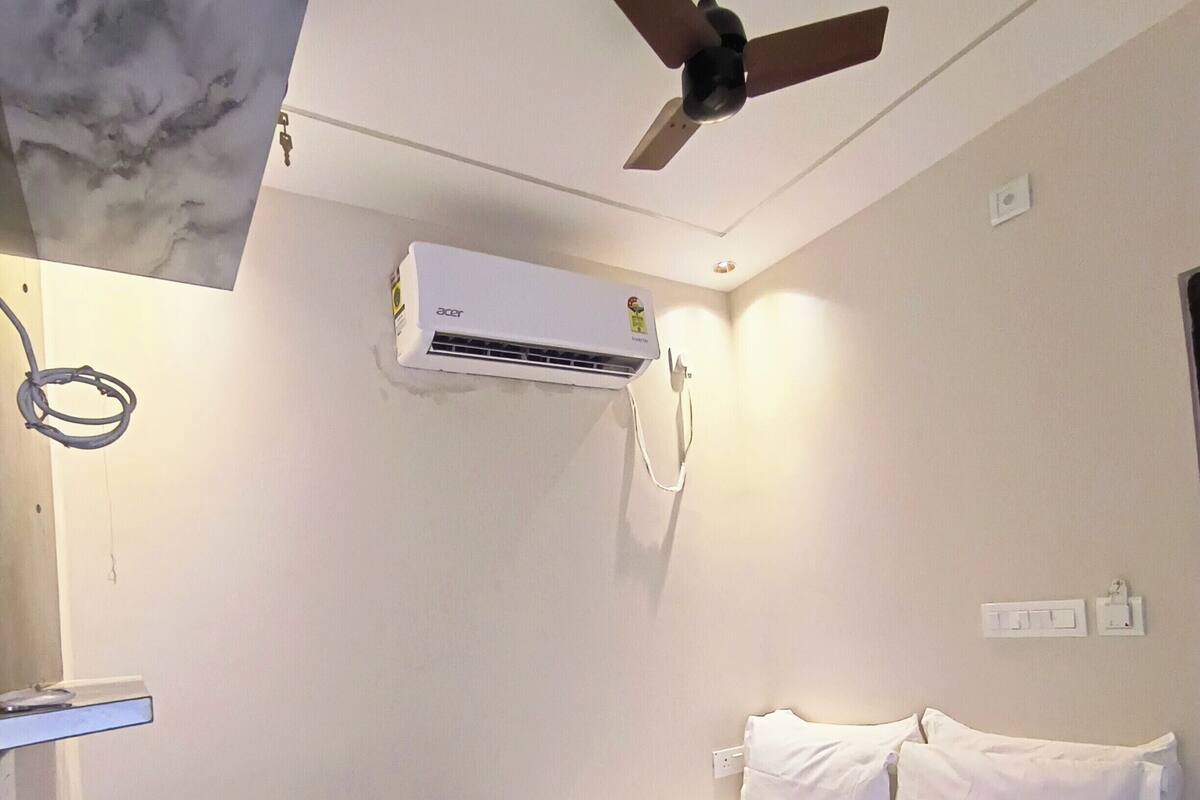Un dormitorio con cama, ventilador de techo y aire acondicionado.