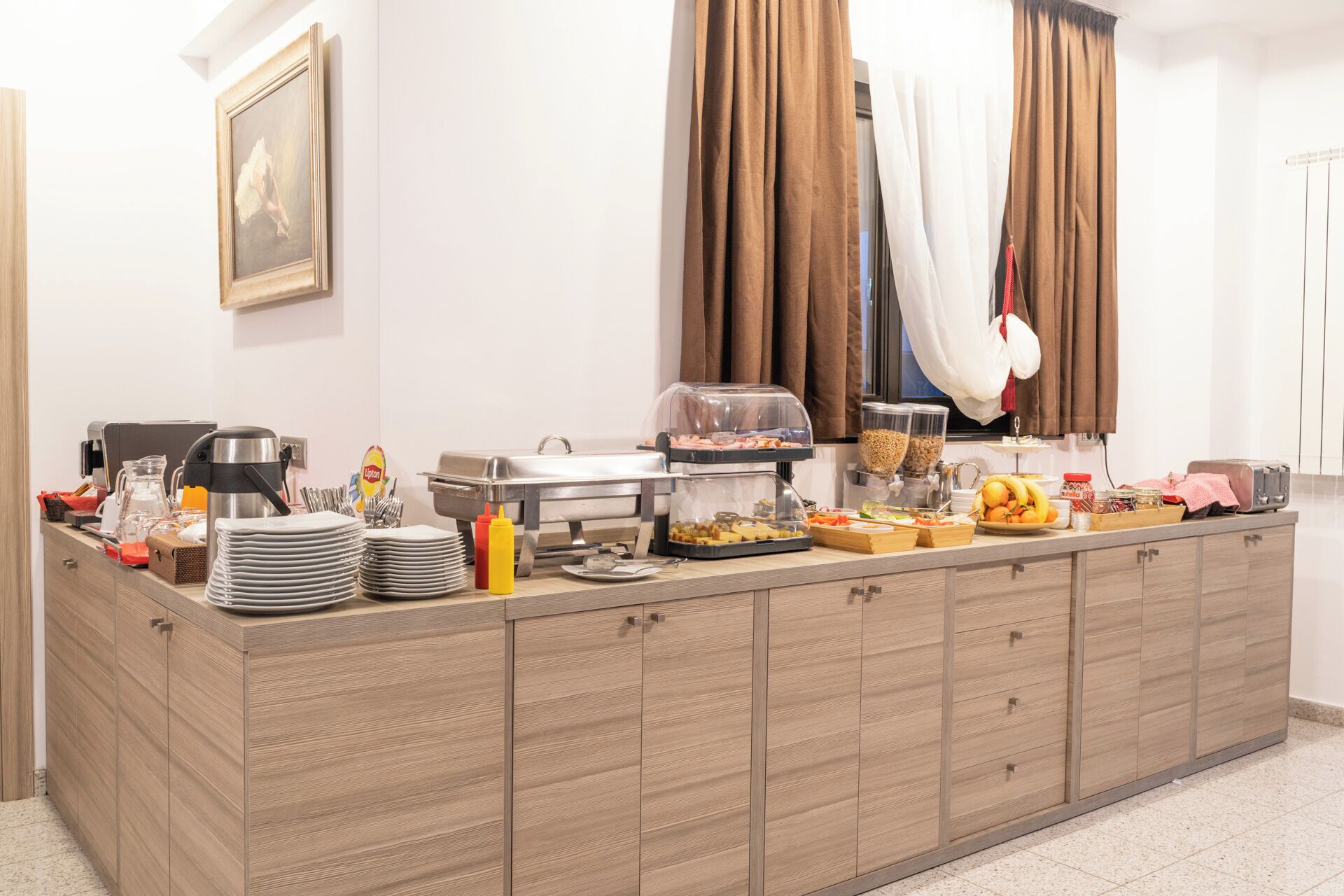 Una mesa de buffet con diversos alimentos, una máquina de café y un lavamanos.
