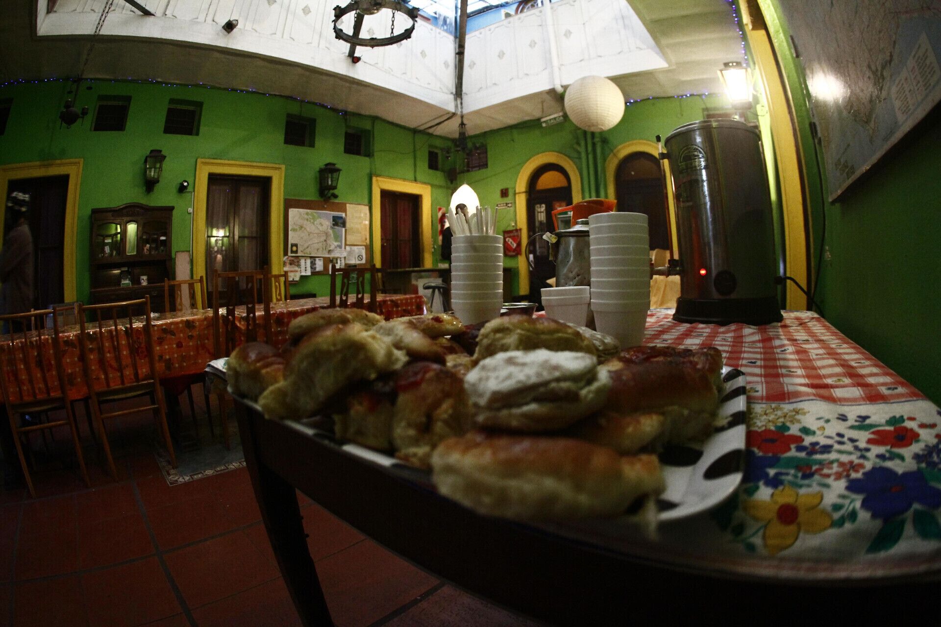 A dining area with a table set for a meal, chairs, and a green wall with windows.