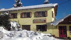 A yellow building with a red door and a sign reading "La Rosa Residencia Familiar". - Residencia Familiar La Rosa (San Carlos de Bariloche)