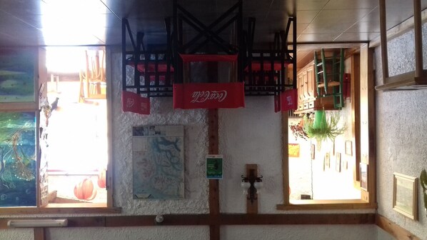 A room with a wooden ceiling, a Coca-Cola banner, a window with a view, and a wall with a map. - Residencia Familiar La Rosa (San Carlos de Bariloche)