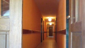A narrow, well-lit hallway with wooden walls and a tiled floor, leading to a door at the end. - Residencia Familiar La Rosa (San Carlos de Bariloche)