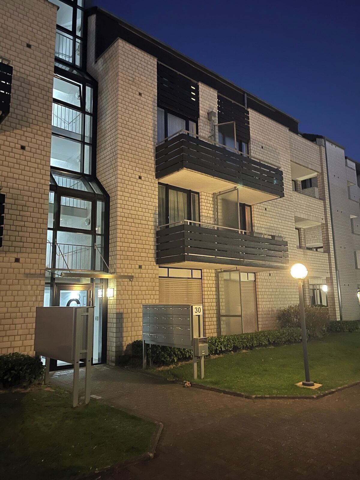 Un edificio residencial de varios pisos con fachada de ladrillo, ventanas grandes y un balcón.