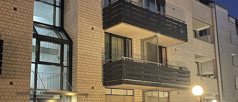 Kerrostalo, jossa on tiiliverhous, suuret ikkunat ja parveke.