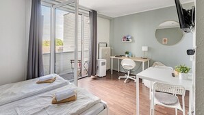 A hotel room with a bed, a desk, a chair, a television, and a sliding glass door to the outside. - Exklusiv | Küche | Office | Streaming+Minibar 6311 (Bonn)