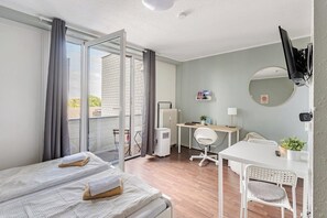 Ein Hotelzimmer mit einem Bett, einem Schreibtisch, einem Sessel, einem Fernseher und einer Schiebetür zum Außenbereich.