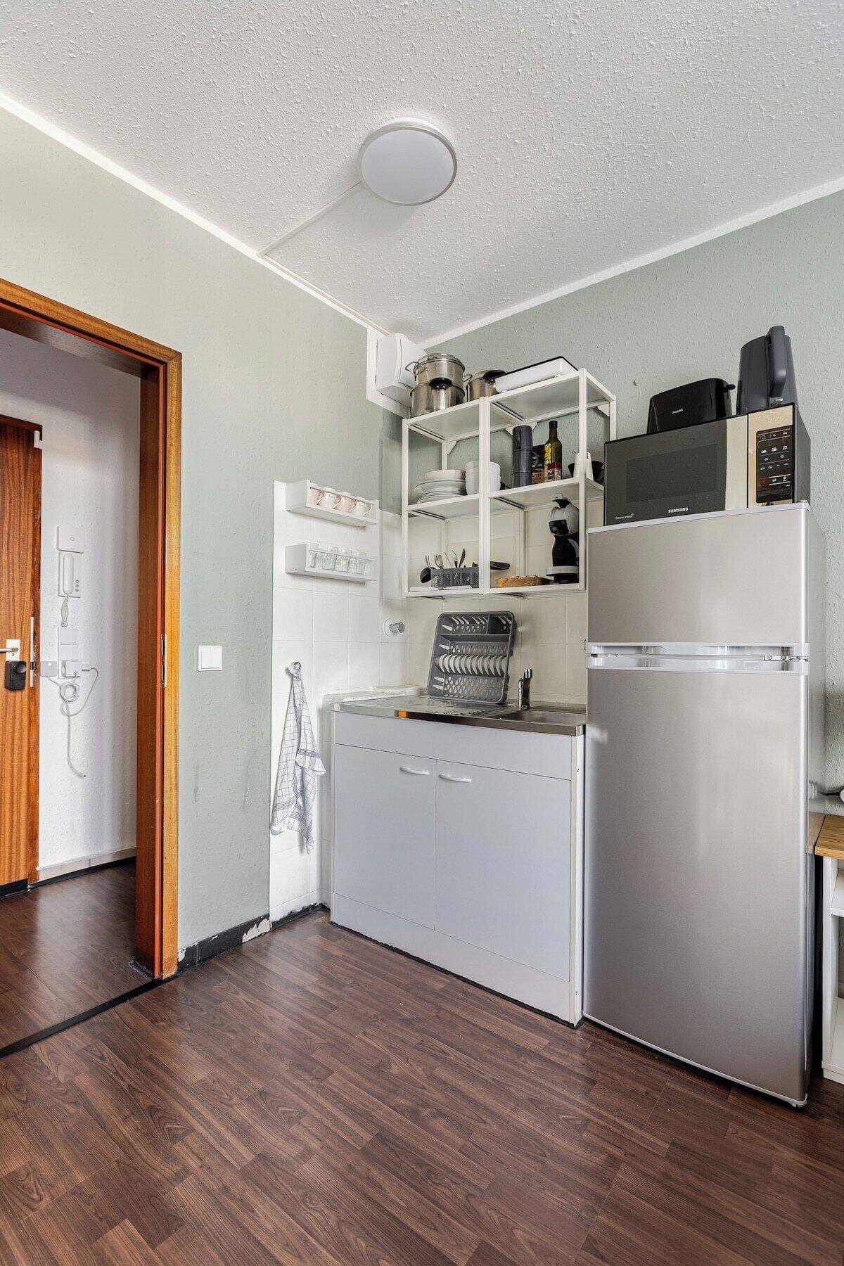 Una cocina compacta con microondas integrado, refrigerador y una pequeña encimera.