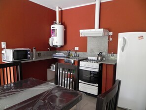 A compact kitchen with a microwave, stove, and refrigerator. - Apart Puerto Inn (Gualeguaychú)