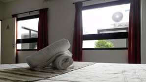 Et hotelværelse med en seng, et vindue med gardiner og udsigt ud.