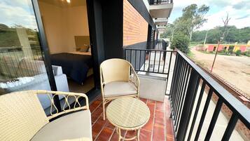 Un balcone con mobili in vimini, un letto e vista sul panorama circostante.