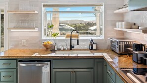 A modern kitchen with a large window, stainless steel appliances, and a granite countertop.
