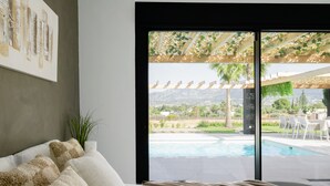 A bedroom with a large window overlooking a pool and outdoor seating area.