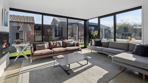 A spacious living room with a large window, a fireplace, and a sofa set. - Lakeside Retreat - Cromwell Holiday Home (Cromwell)