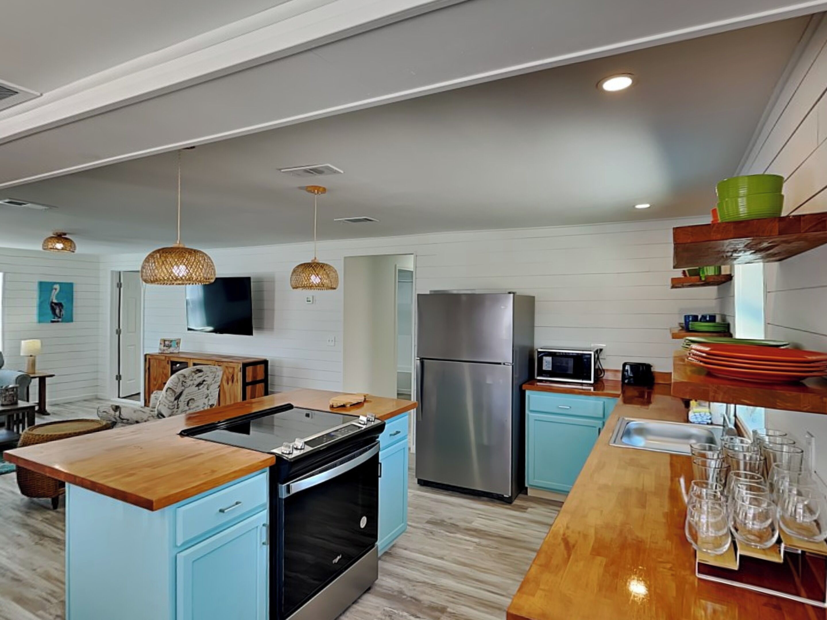 A modern kitchen with a central island, built-in oven, stainless steel refrigerator, and a microwave.