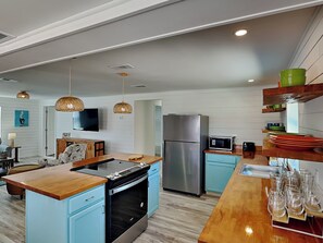 Eine moderne Küche mit Kochinsel, eingebautem Backofen, Edelstahlkühlschrank und Mikrowelle.