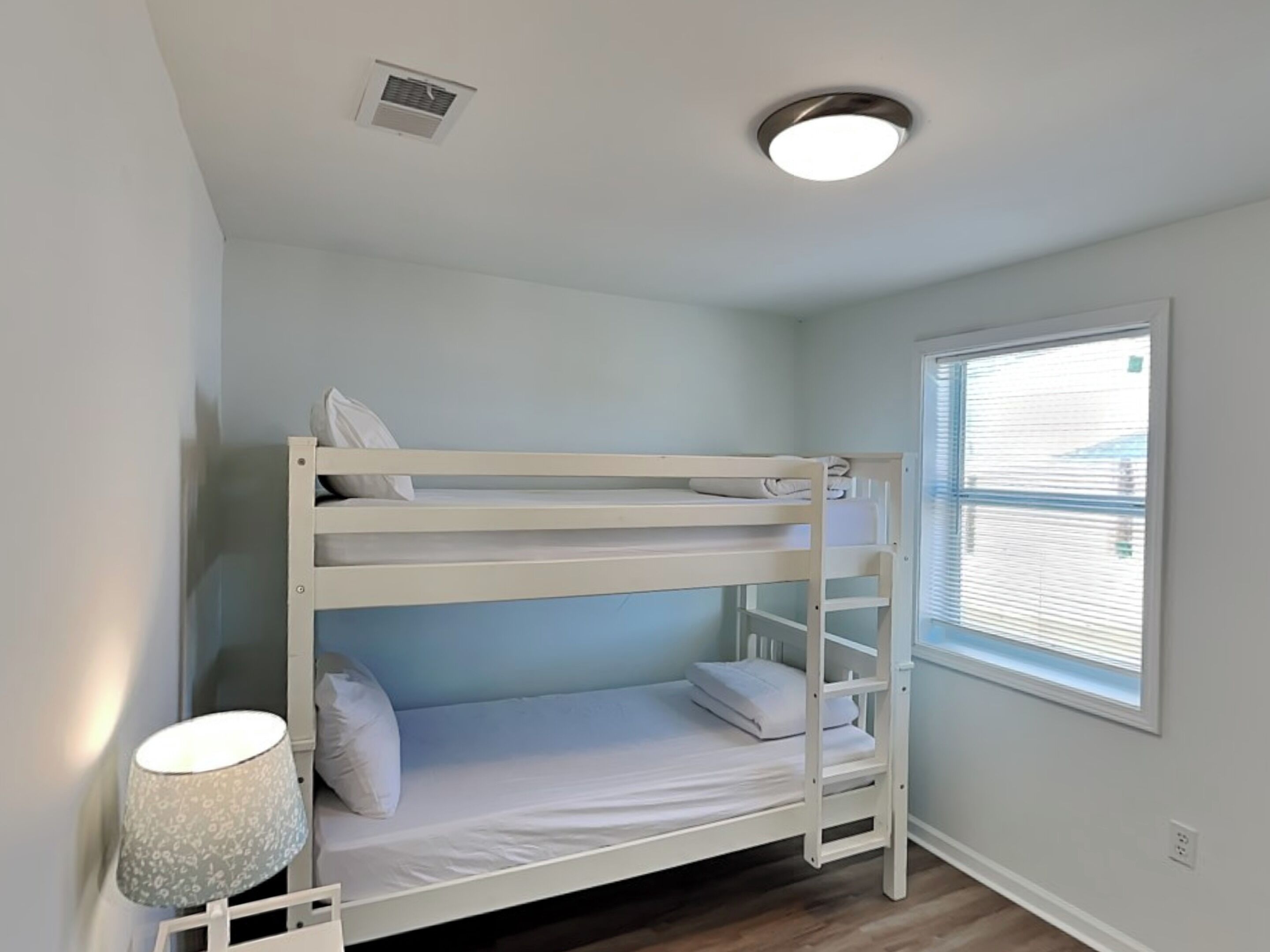 A bunk bed room with a window and a lamp.