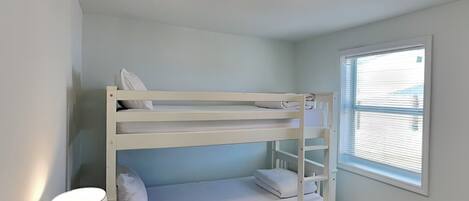 A bunk bed room with a window and a lamp.