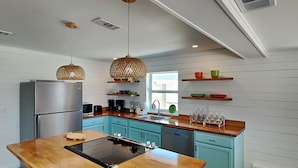 A modern kitchen with a central island, built-in appliances, and wooden cabinetry. - Salt & Sea by Resort Collection (Panama City Beach)