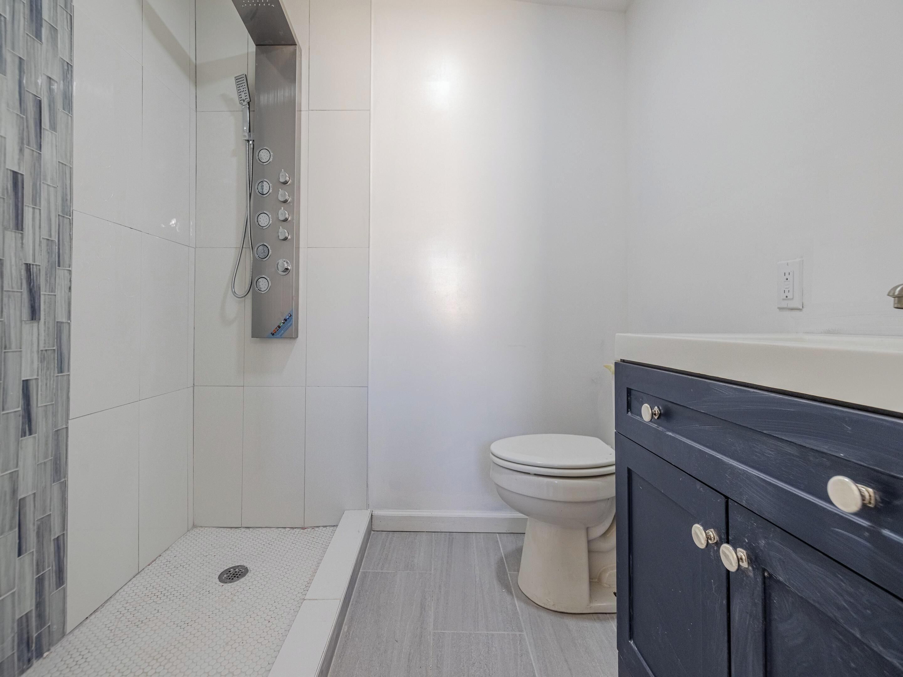 A bathroom with a shower, toilet, and dark-colored vanity.