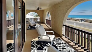 A balcony with a view of the ocean, a ceiling fan, and a patterned rug. - Lion On The Beach by Resort Collection (Panama City Beach)