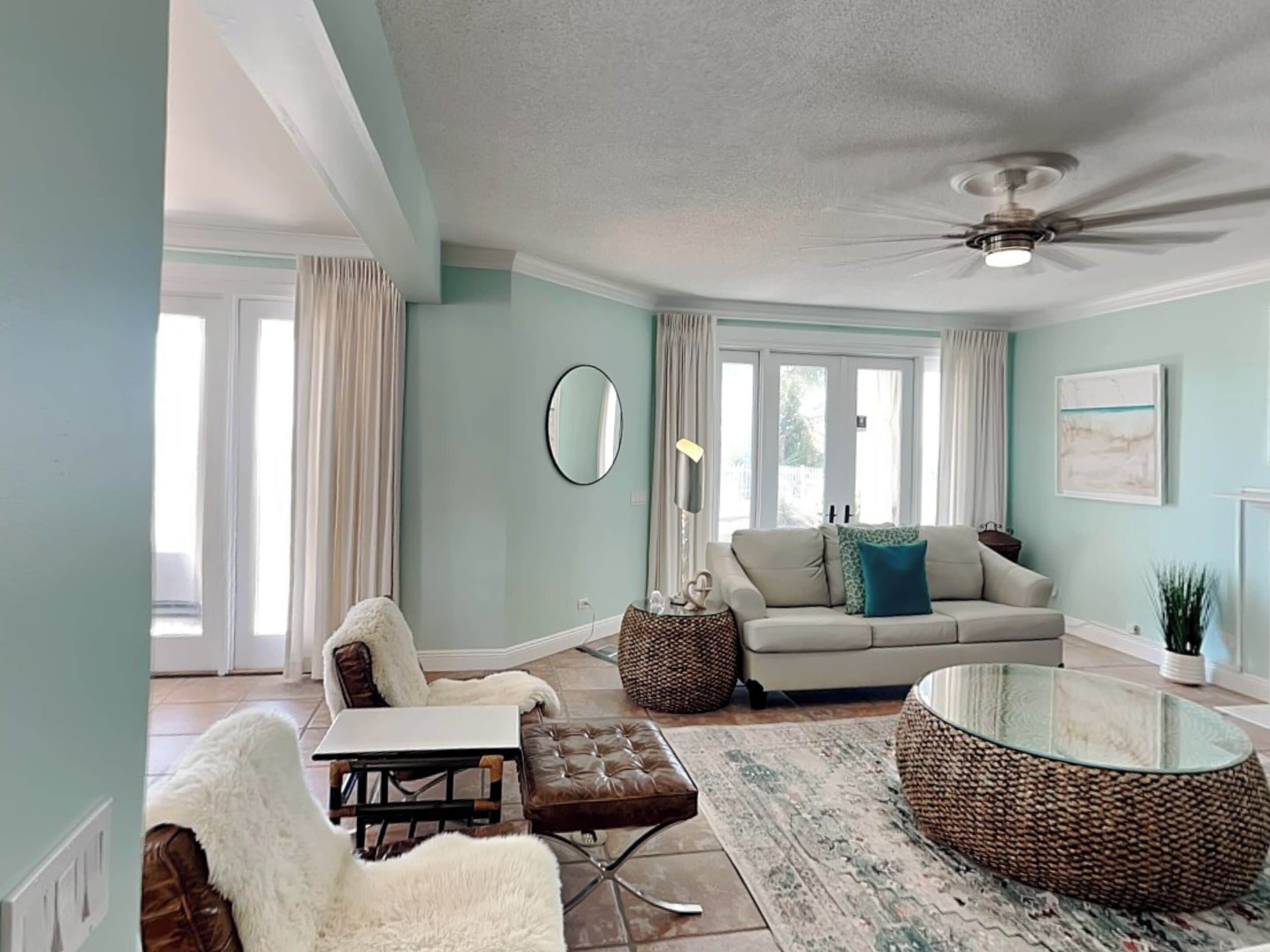 A living room with a sofa, armchair, coffee table, and a ceiling fan.