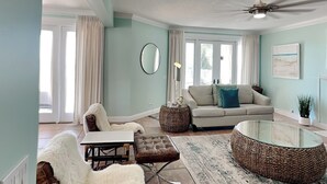 A living room with a sofa, armchair, coffee table, and a ceiling fan. - Lion On The Beach by Resort Collection (Panama City Beach)