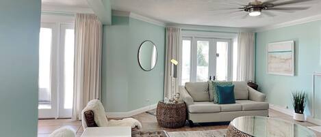 A living room with a sofa, armchair, coffee table, and a ceiling fan.