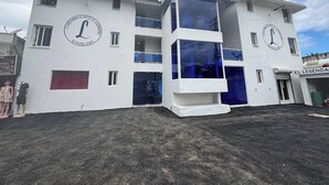 A hotel with a white facade, large windows, and a prominent logo. - Room-condo Facing the Pool in the Heart (Sosúa)